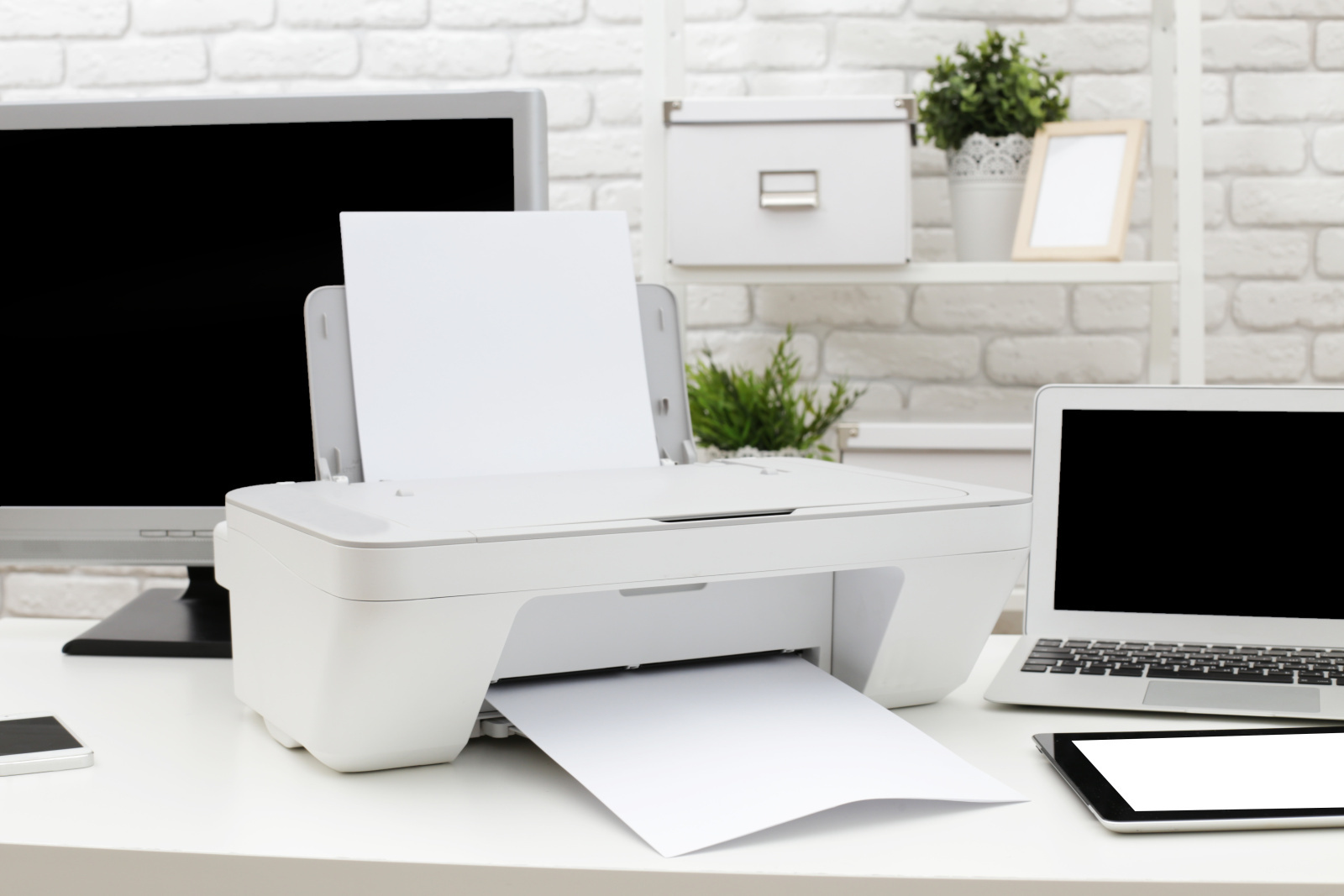 Drucker mit Xeroxpapier neben einem Laptop.